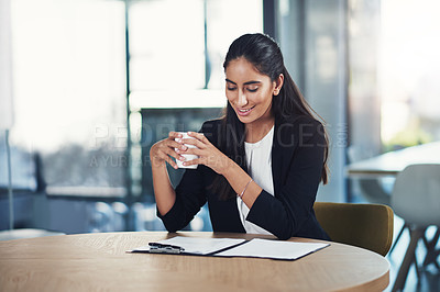 Buy stock photo Shot of a young businesswoman drinking coffee while working in an office