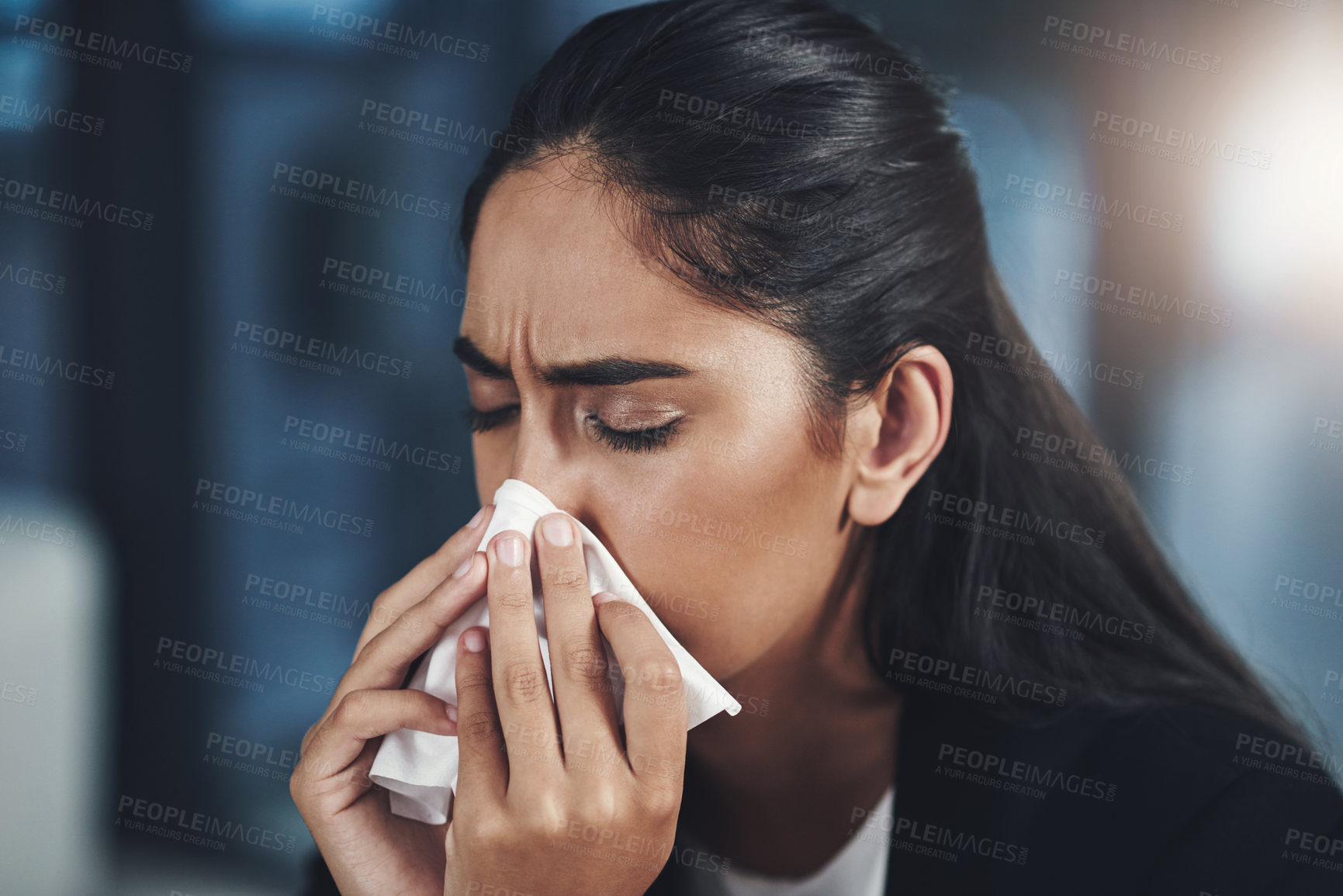 Buy stock photo Shot of a young businesswoman blowing her nose in an office