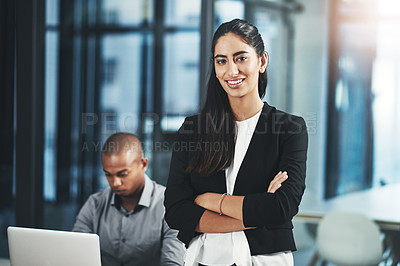 Buy stock photo Portrait of a young businesswoman standing in an office with her colleague in the background