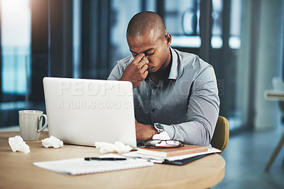 Buy stock photo Shot of a young businessman suffering with a headache while working in an office