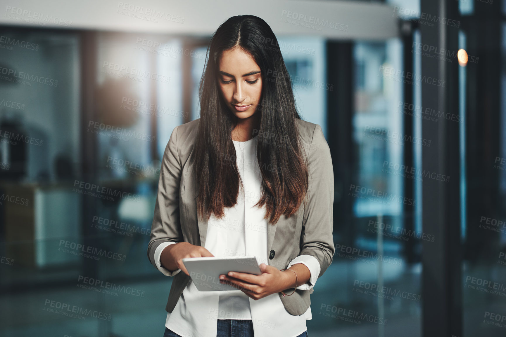 Buy stock photo Shot of a young businesswoman working on a digital tablet in an office