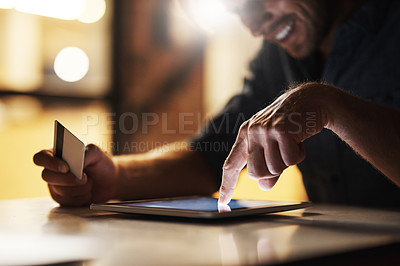 Buy stock photo Cropped shot of an unrecognizable male designer using his digital tablet to shop online while working in the office