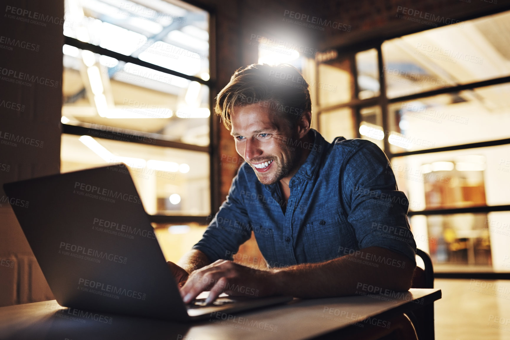 Buy stock photo Cropped shot of a handsome young male designer looking pleased while working late in his office