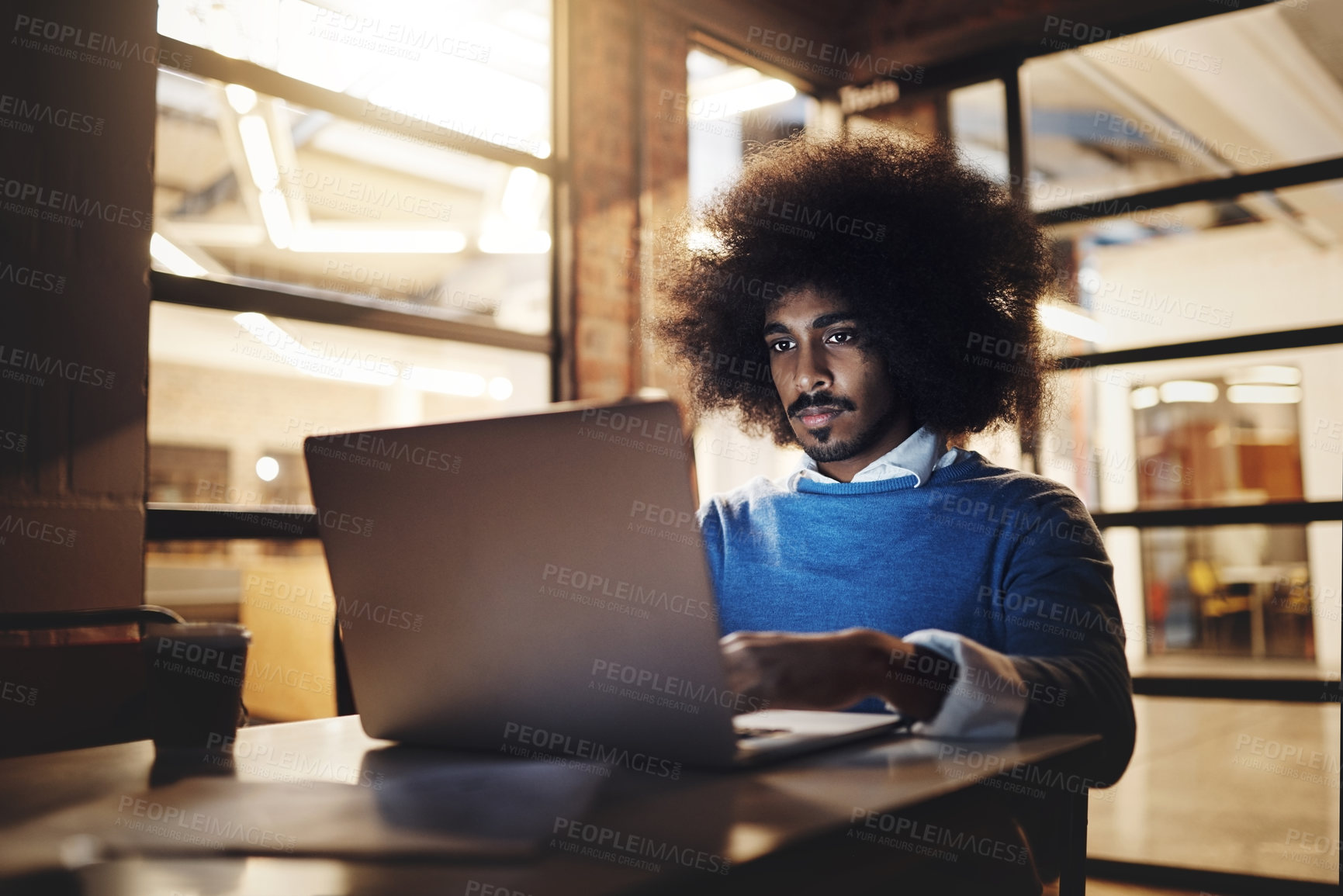 Buy stock photo Cropped shot of a handsome young male designer using his laptop while working late in the office