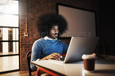 Buy stock photo Cropped shot of a handsome young male designer using his laptop while working late in the office