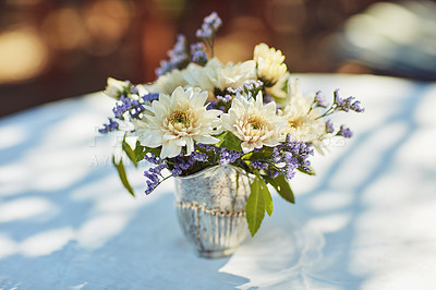 Buy stock photo Shot of a metal vase filled with flowers on table at a tea party outside