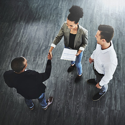 Buy stock photo High angle shot of two businesspeople shaking hands in an office