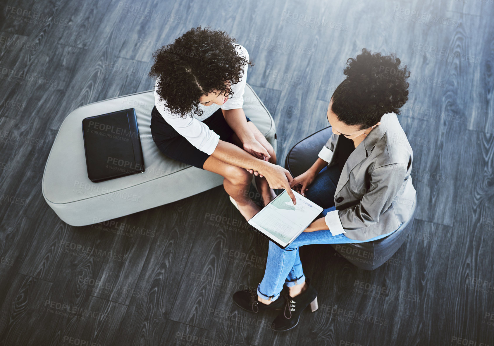 Buy stock photo High angle shot of two businesswomen working together on a digital tablet in an office