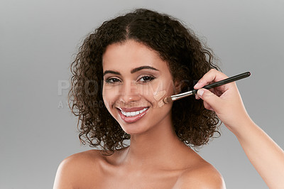 Buy stock photo Studio shot of a beautiful young woman applying foundation with a make up brush against a gray background