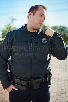 Buy stock photo Cropped shot of a handsome young policeman radioing in with headquarters