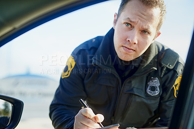 Buy stock photo Cropped shot of a handsome young male traffic officer issuing a ticket at a roadblock