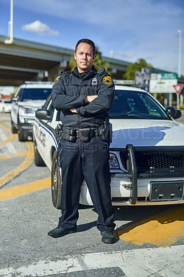 Buy stock photo Full length portrait of a handsome young policeman standing with his arms crossed while out on patrol