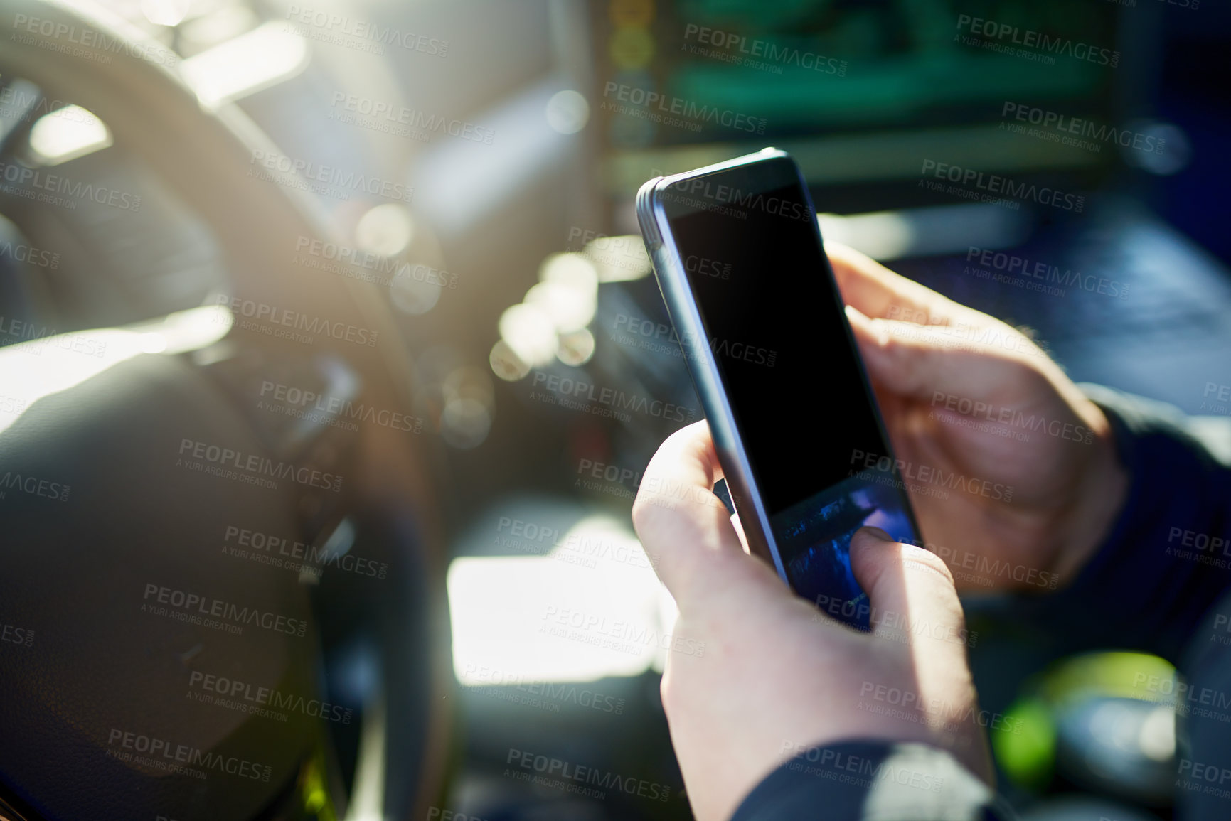 Buy stock photo Cropped shot of an unrecognizable male police officer using his cellphone while out on patrol