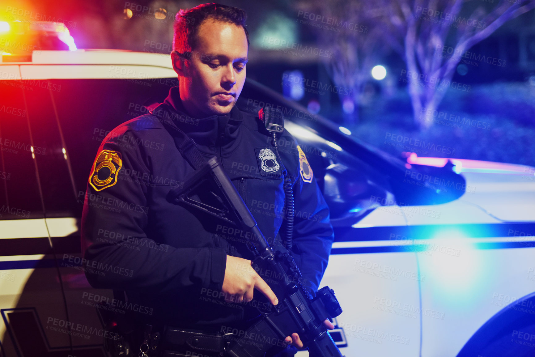 Buy stock photo Cropped shot of a handsome young policeman standing with his assault rifle while out on patrol