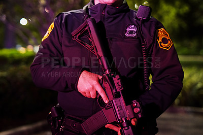 Buy stock photo Cropped shot of an unrecognizable policeman standing with his assault rifle while out on patrol