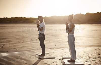 Buy stock photo Shot of a young couple practising yoga together on the beach