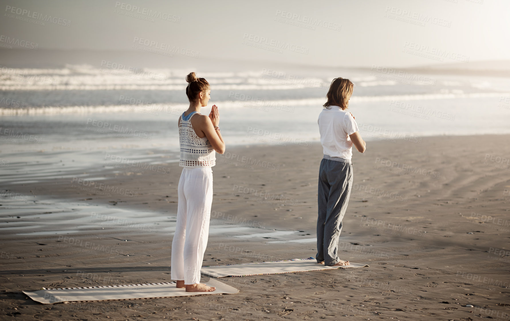 Buy stock photo Shot of a young couple practising yoga together on the beach