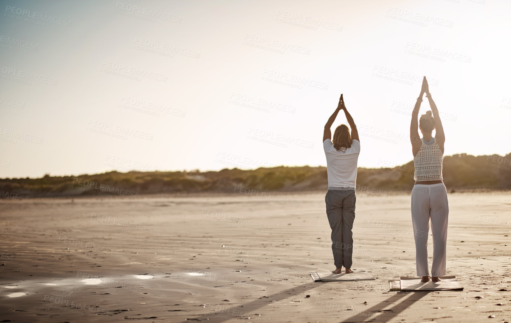 Buy stock photo Rearview shot of an unrecognizable couple practising yoga on the beach