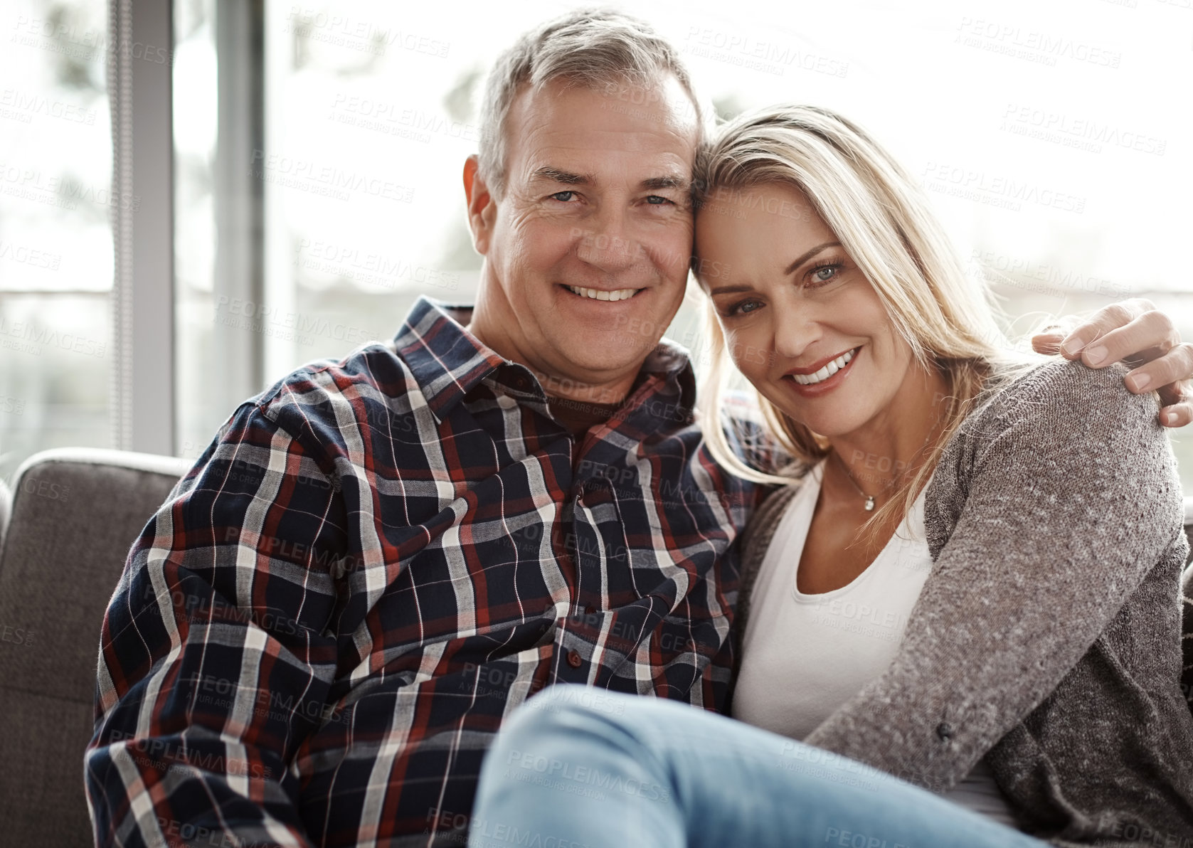 Buy stock photo Shot of an affectionate mature couple relaxing together on the sofa at home
