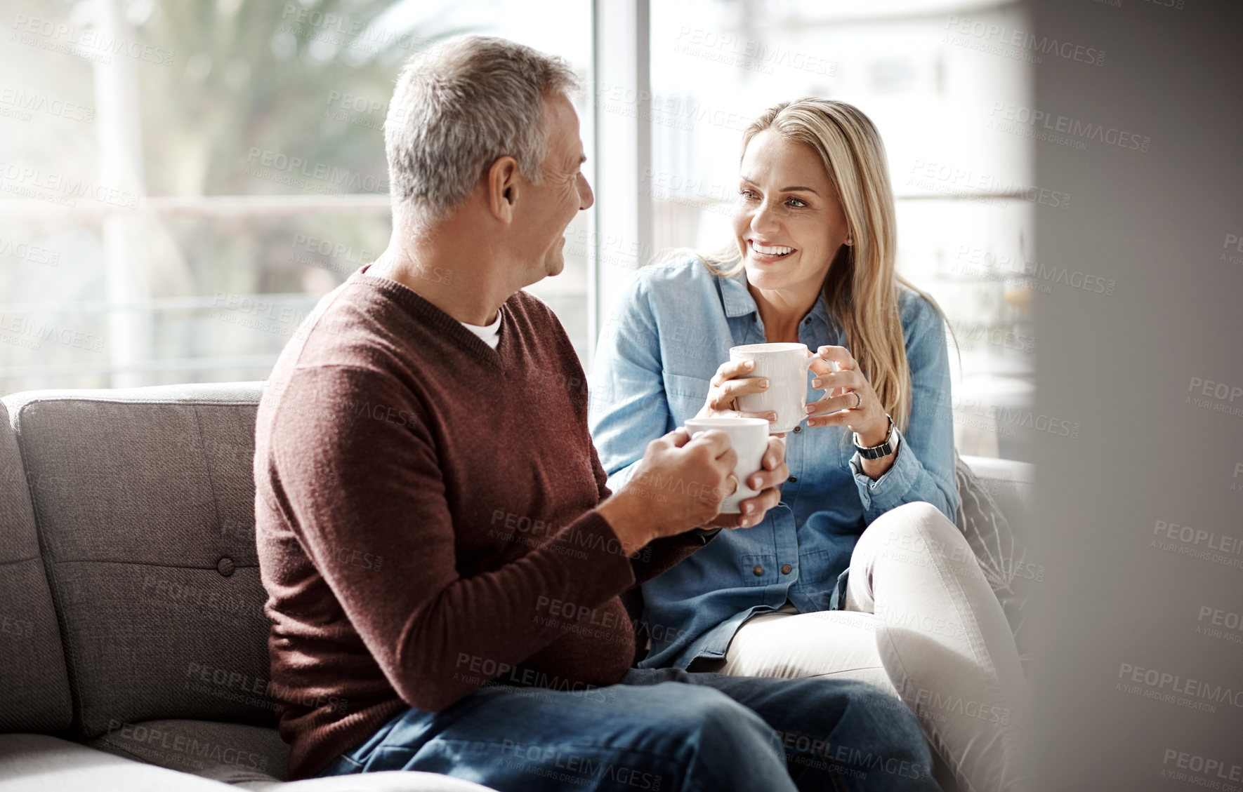 Buy stock photo Shot of a mature couple enjoying a relaxing coffee break on the sofa together at home