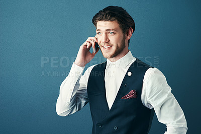 Buy stock photo Studio shot of a handsome young businessman making a phonecall against a blue background