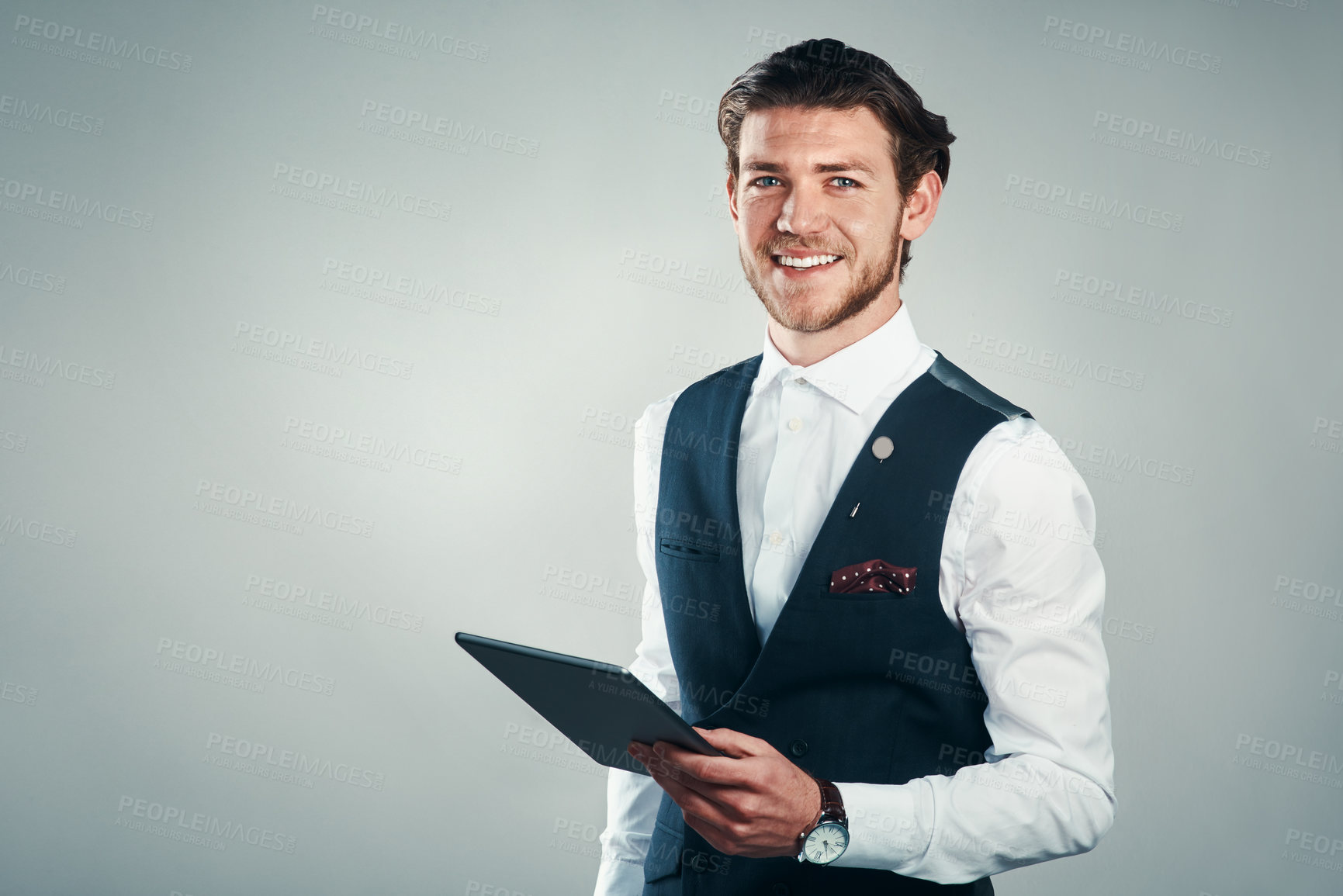 Buy stock photo Studio shot of a handsome young businessman using a tablet against a grey background