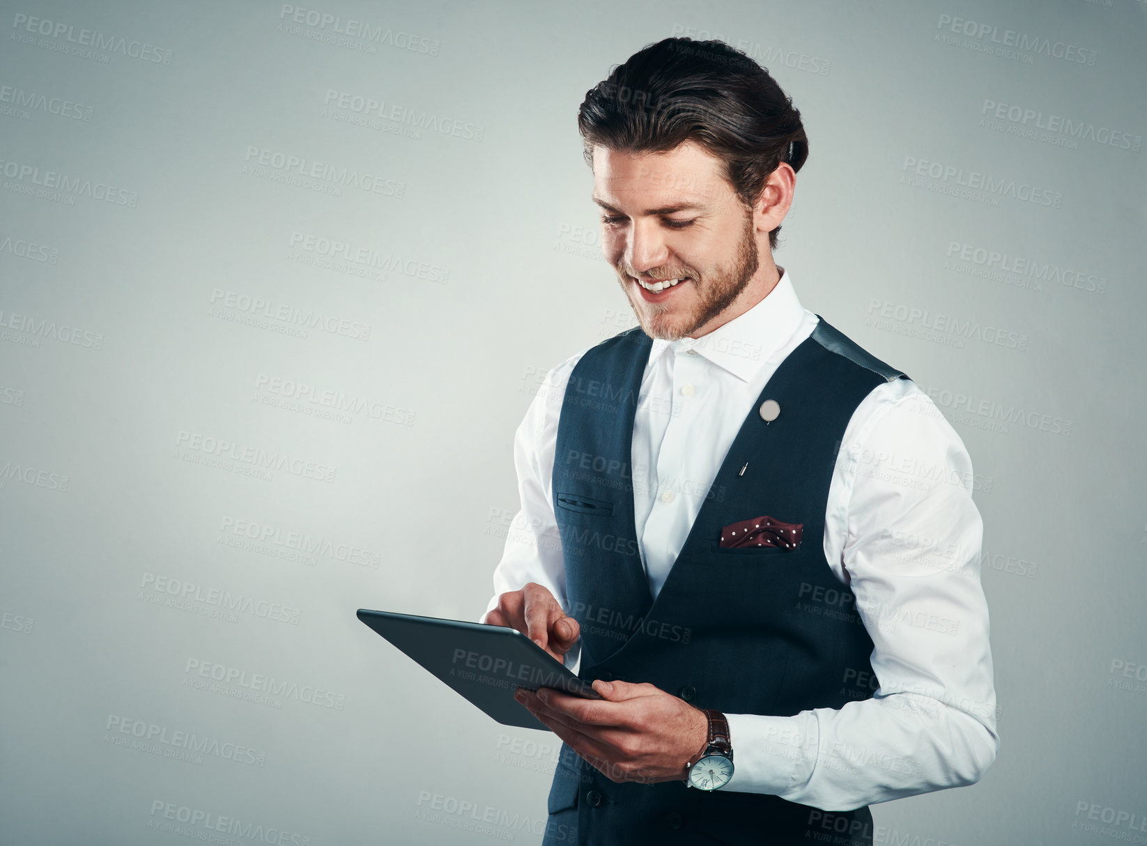 Buy stock photo Studio shot of a handsome young businessman using a tablet against a grey background
