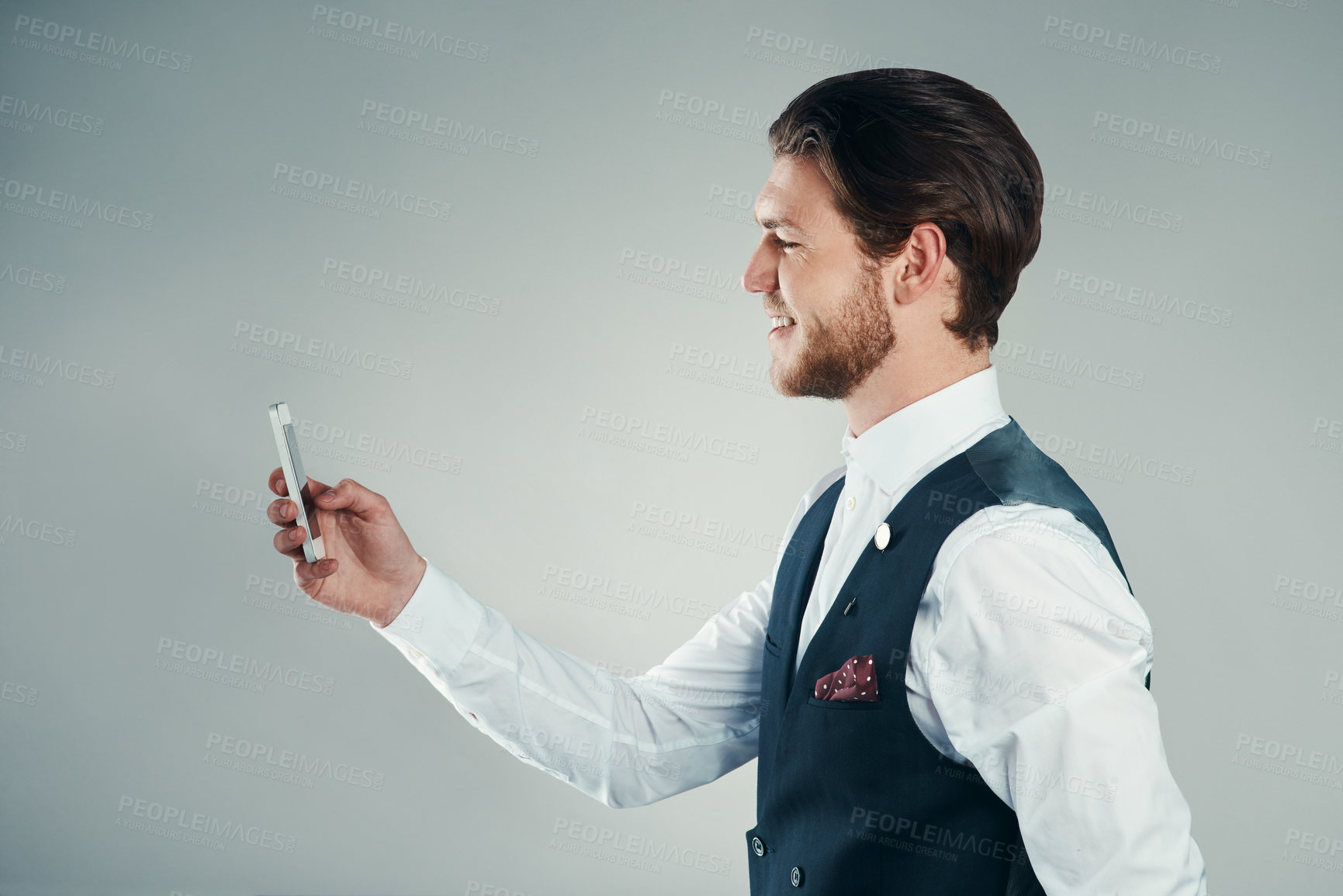 Buy stock photo Studio shot of a handsome young businessman sending a text message against a grey background