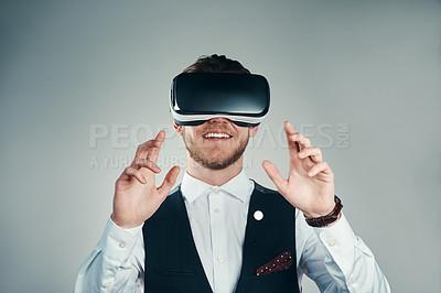 Buy stock photo Studio shot of a handsome young businessman using a vr headset against a grey background