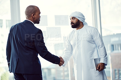 Buy stock photo Shot of two businessmen shaking hands in a modern office