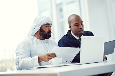 Buy stock photo Shot of two businessmen using a digital tablet and laptop while having a discussion in a modern office