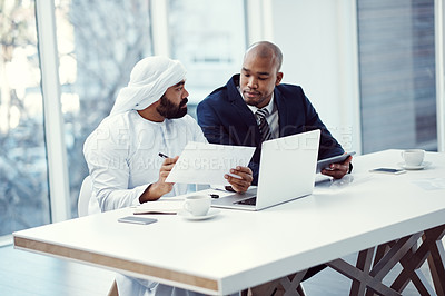 Buy stock photo Shot of two businessmen using a digital tablet and laptop while having a discussion in a modern office