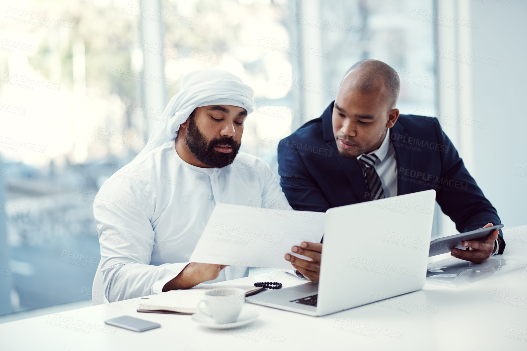 Buy stock photo Shot of two businessmen using a digital tablet and laptop while having a discussion in a modern office