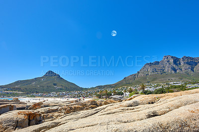 Buy stock photo Landscape of mountains and moon on blue sky with copy space. Beautiful rock outcrops of mountaintops near the coastline or bay area. View of Devils Peak and Table Mountain in Cape Town, South Africa