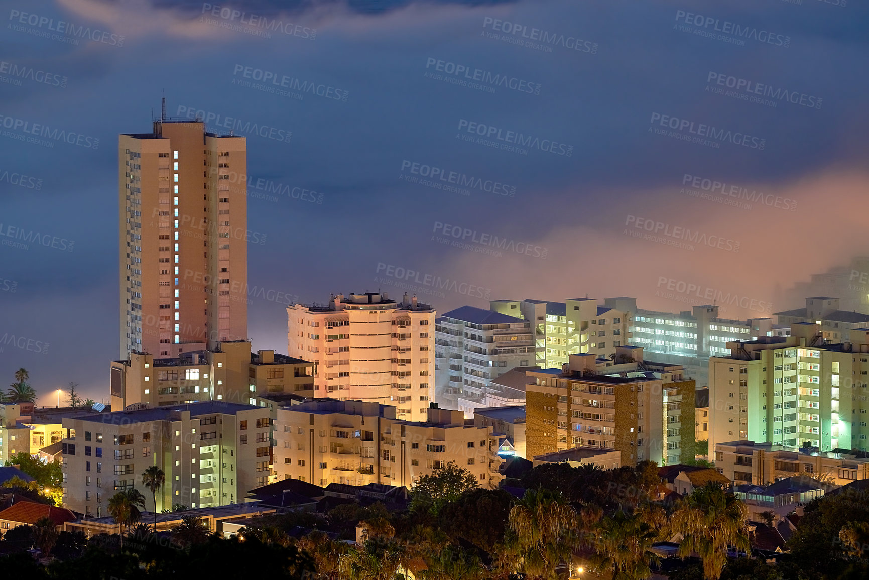 Buy stock photo Aerial view of fancy hotels and apartment buildings lit up brighly in Sea Point, Cape Town, South Africa at night. An overcast and cloudy evening at a tourist resort during winter in the Western Cape