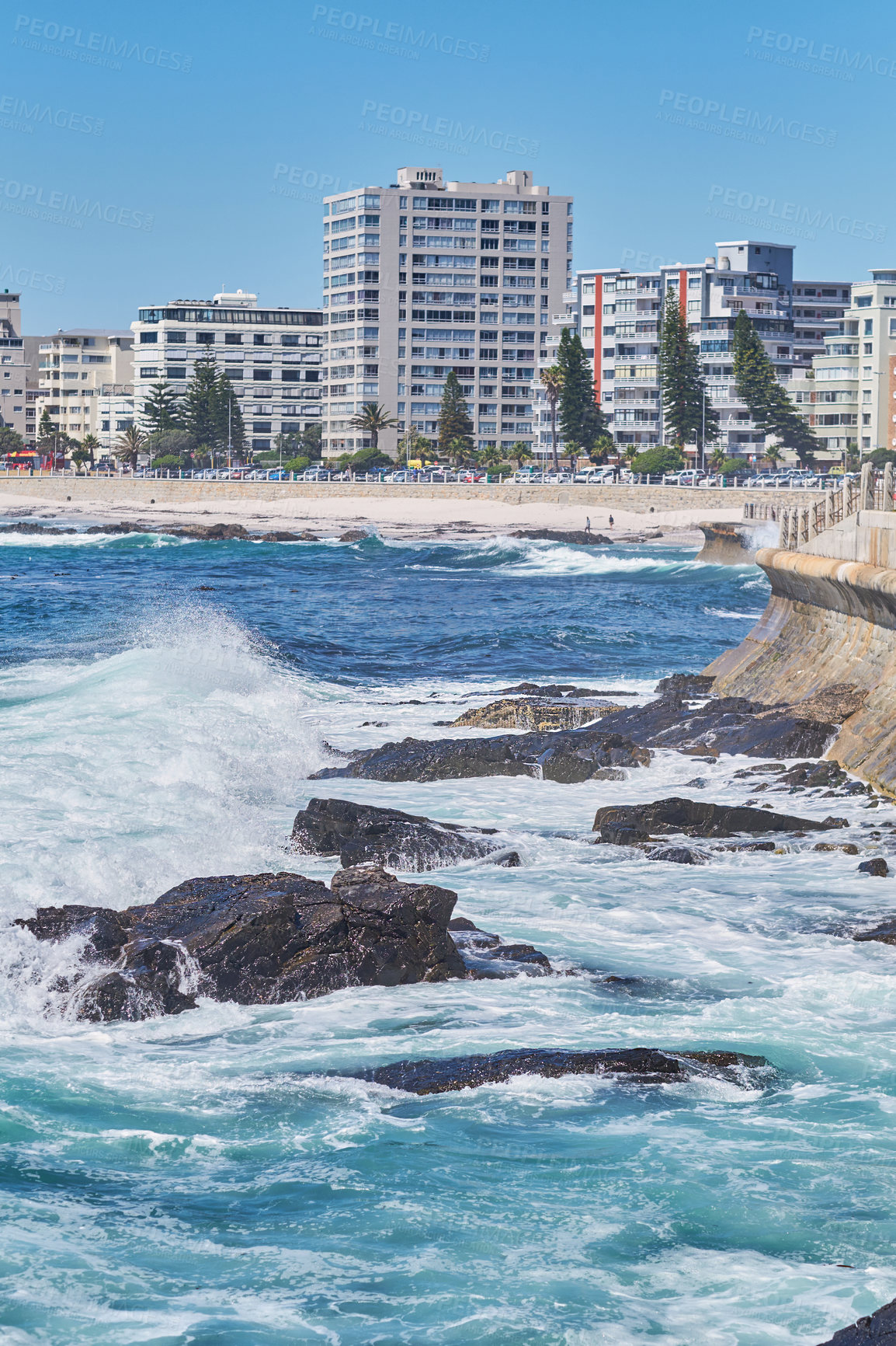 Buy stock photo Rocky sea near city housing. Tall apartment buildings beside a beach on a sunny day. A popular summer vacation tourist location in South Africa. Luxury vacation resort by a blue ocean in Sea Point