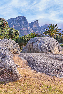 Buy stock photo Camps Bay, Table Mountain National Park, Cape Town, South Africa during suet on a summer day. Rocks and boulders against a majestic mountain background with lush green palm trees and a clear blue sky