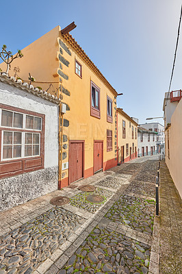 Buy stock photo Road, stone or buildings in city for architecture, houses or blue sky in Spain. Santa Cruz, travel or cobblestone in neighborhood for heritage town, history or village design in Europe for aesthetic