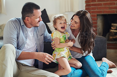 Buy stock photo Cropped shot of a young mother and father spending time with their adorable little daughter in the living room at home