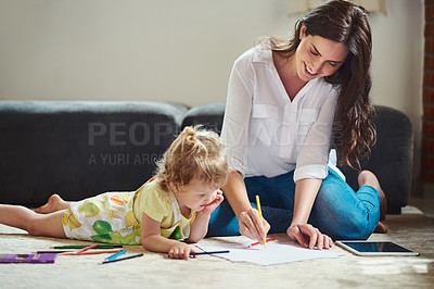 Buy stock photo Cropped shot of a beautiful young mother helping her adorable little daughter colour in and draw in the living room at home