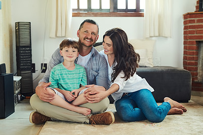 Buy stock photo Portrait of a young mother and father spending time with their adorable little son in the living room at home