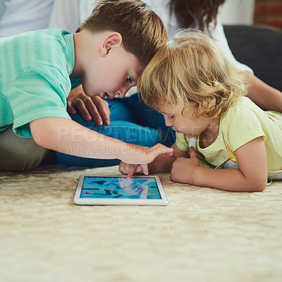 Buy stock photo Cropped shot of an adorable brother and sister using a tablet together on the floor in the living room at home