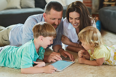 Buy stock photo Cropped shot of a young family using a tablet together on the floor in the living room at home