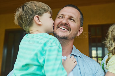Buy stock photo Cropped shot of an adorable little boy kissing his father on the cheek in the backyard at home