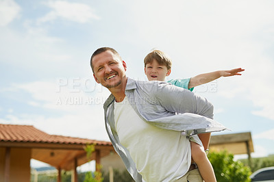 Buy stock photo Cropped shot of a young handsome father giving his adorable little son a piggyback ride in the backyard at home