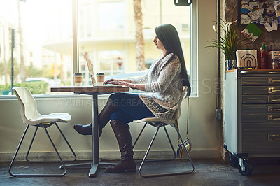 Buy stock photo Shot of a young woman using a laptop in a cafe