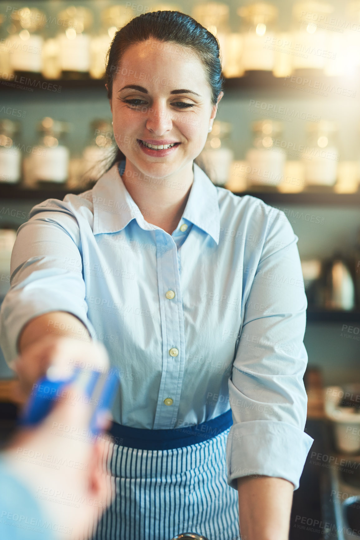 Buy stock photo Shot of a young woman receiving a credit card payment from a customer in a cafe
