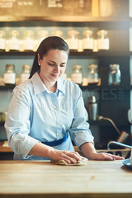Buy stock photo Shot of a young woman cleaning a countertop in her cafe