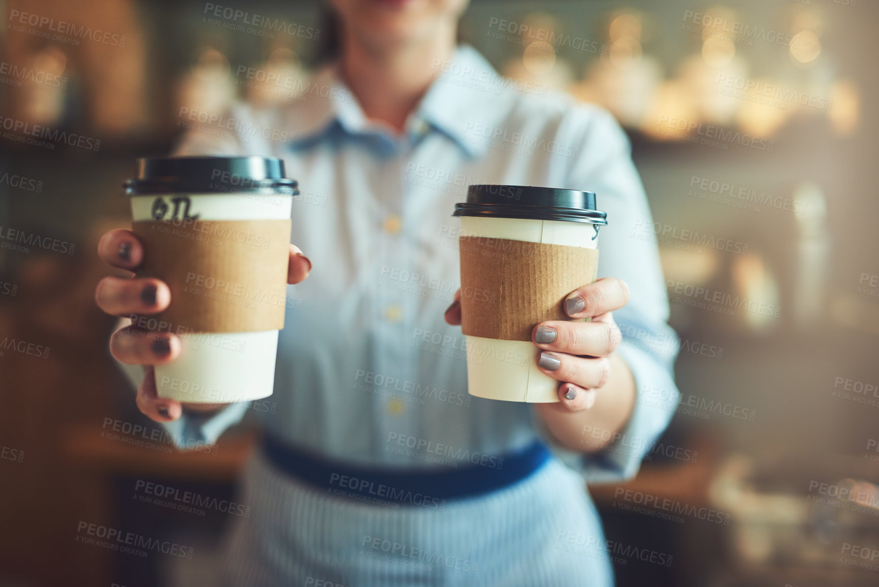 Buy stock photo Closeup shot of an unrecognizable barista holding cups of coffee in a cafe