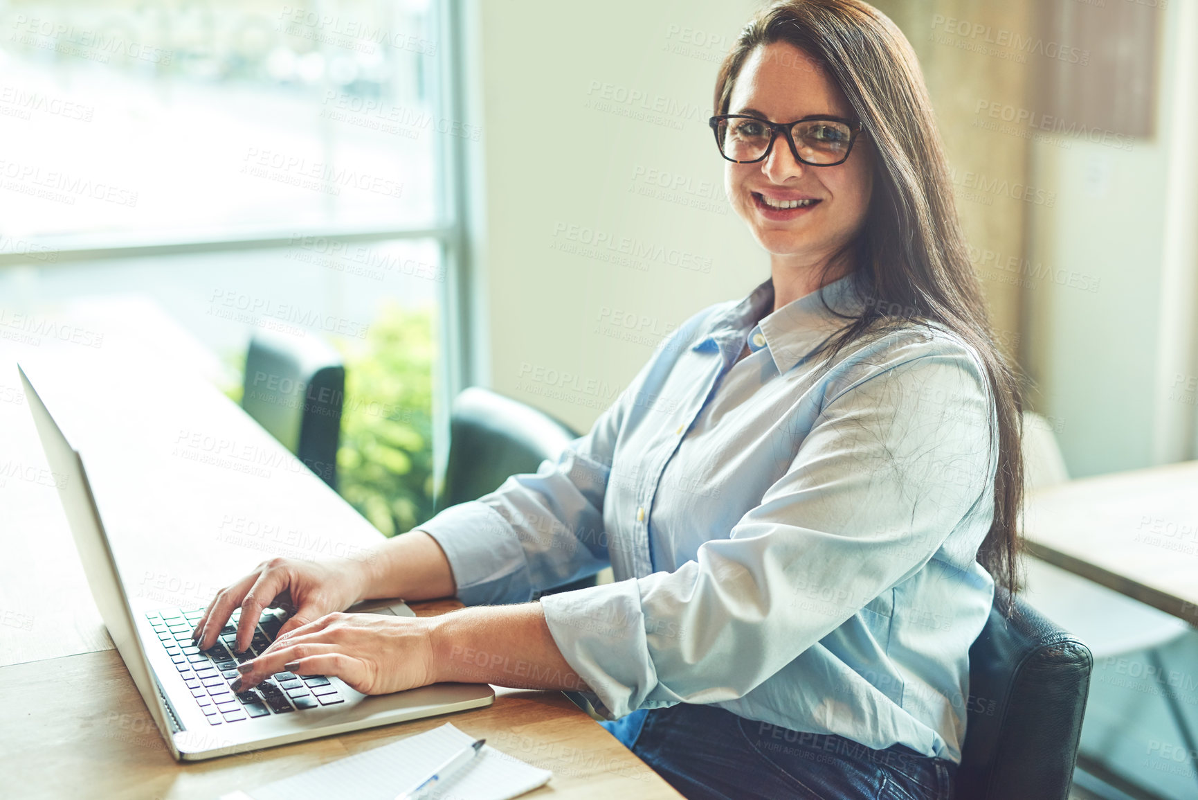 Buy stock photo Portrait of a young woman using a laptop in a cafe